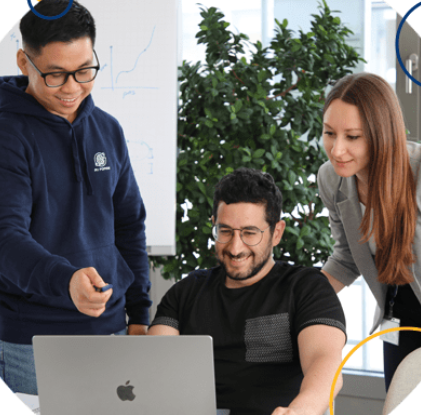 Three people collaborating around a laptop